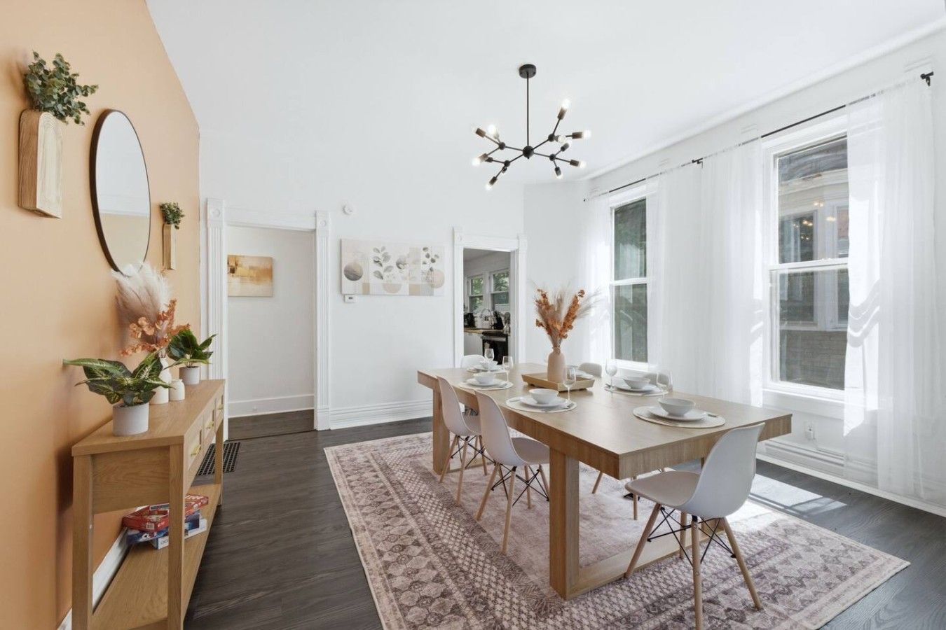 Un coin repas avec une table en bois, des chaises blanches et un lustre.
