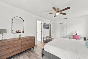 A bedroom with a bed, a dresser, a mirror, a ceiling fan, and a television. - 4 BR Regal Palms Haven Near Disney & Golf (Davenport)