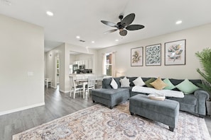 A modern living room with a grey sofa, ottoman, and patterned rug. - 4 BR Regal Palms Haven Near Disney & Golf (Davenport)
