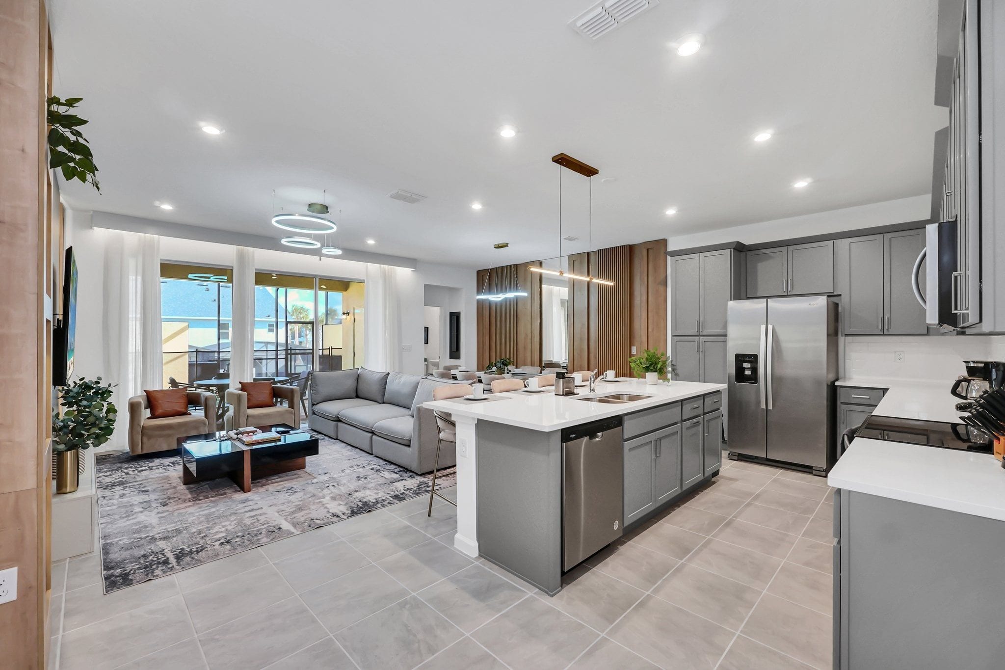 A modern kitchen with a central island, grey cabinetry, and stainless steel appliances.