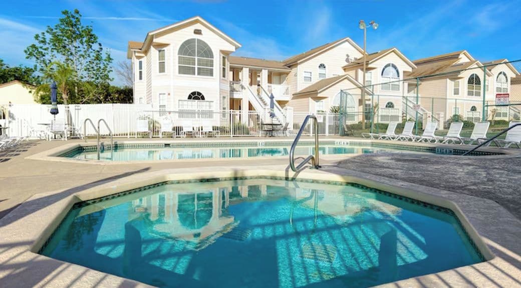 A hotel with a swimming pool, multiple buildings, and a clear sky.