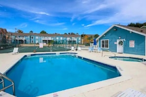A swimming pool with a clear blue water, surrounded by a fenced area, and adjacent to a building with a blue exterior. - 3BR Condo Near Disney w/ Pool, gym & Balcony (Kissimmee)