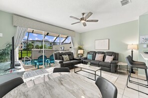 A living room with a pool view, a ceiling fan, and a dining area with a marble table. - 3BR Tropical Escape With Private Pool (Kissimmee)