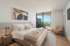 A modern hotel room with a large bed, a view of the sea, and a balcony with a chair. - Savoy Luxe - Luxury 3-bed w/ pool (Funchal)