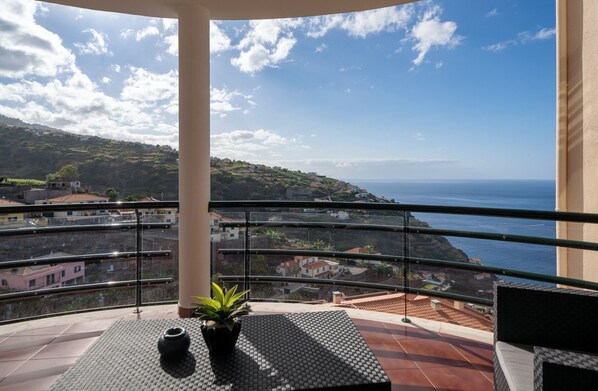A balcony with a view of a coastal town and the sea.
