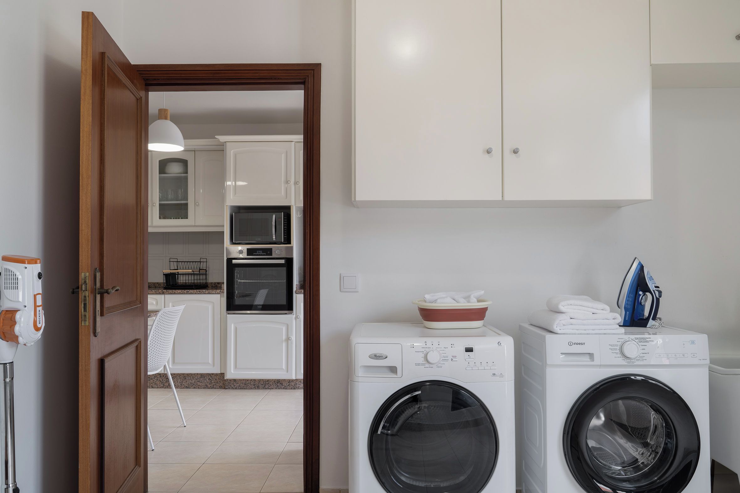 A laundry area with two washing machines, a microwave, and a sink.