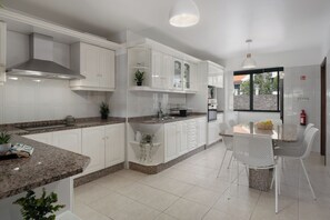 Eine moderne Küche mit weißen Schränken, Granit Arbeitsplatten und einem Essbereich mit weißen Stühlen.
