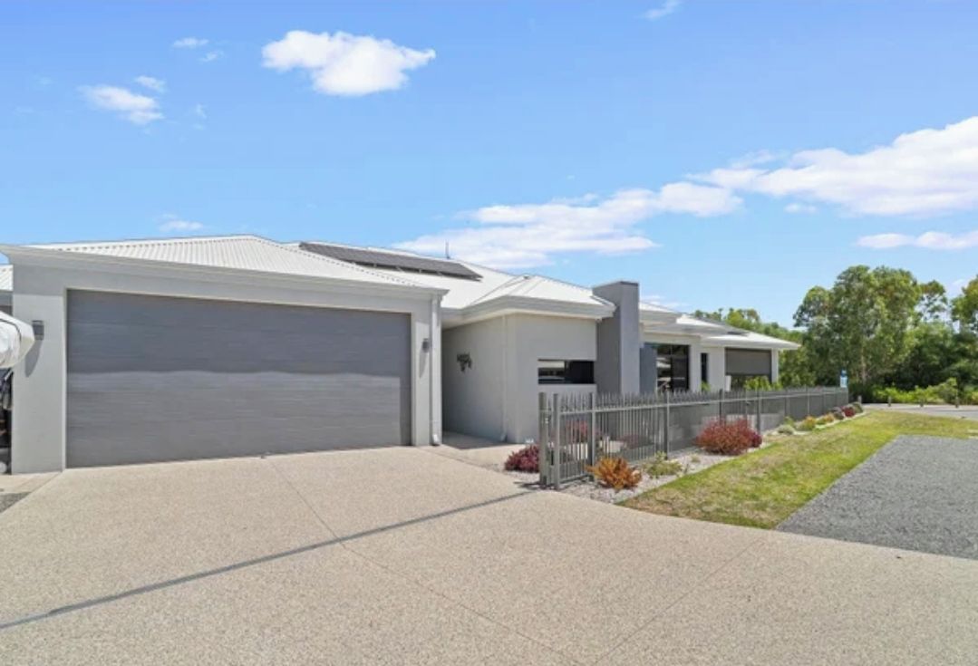 A modern two-story residential building with a garage, a covered driveway, and a landscaped front yard.