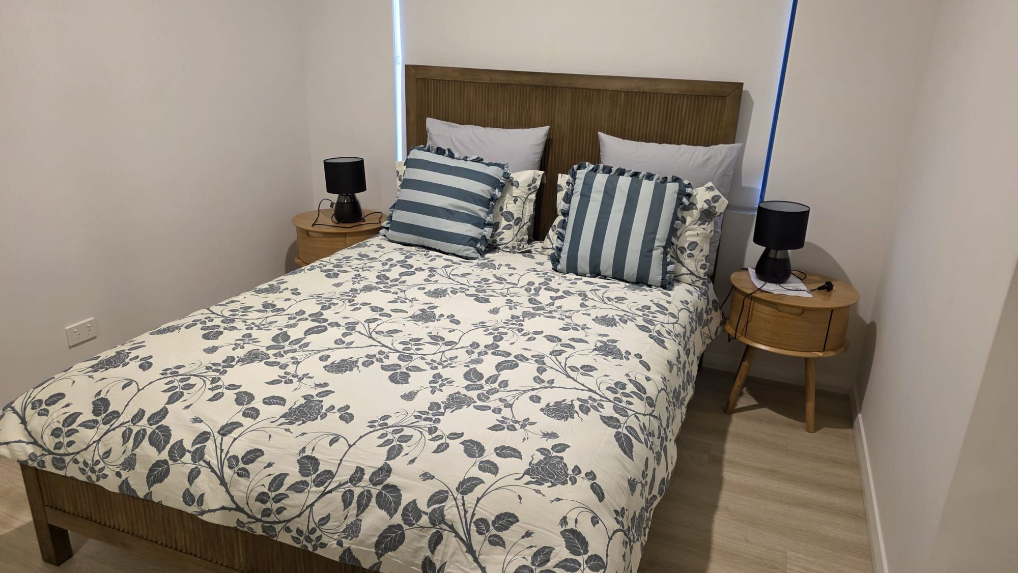 A bed with a floral bedspread, two bedside tables with lamps, and a wooden headboard.