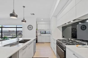Una cucina moderna con isola centrale, elettrodomestici in acciaio inossidabile e illuminazione a sospensione.
