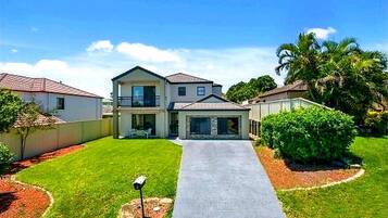 A two-story residential house with a front driveway, a balcony, and a well-maintained lawn.