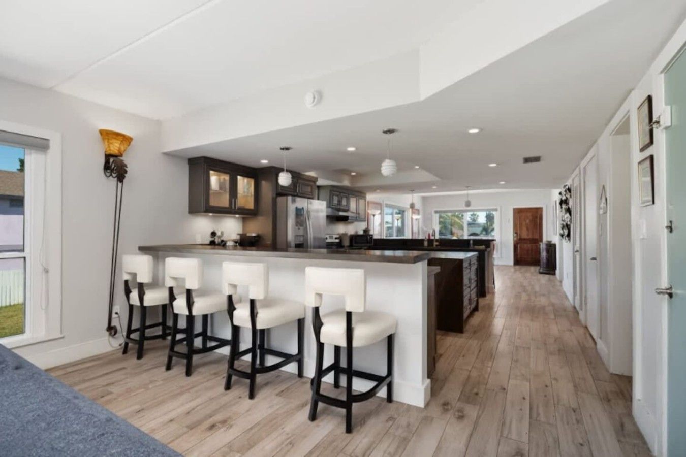 A modern kitchen with a central island, bar stools, and a view of the outdoors.