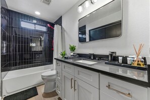 A modern bathroom with a bathtub, toilet, and sink. - Austin Hideaway | 3BR Home with Private Backyard (Austin)