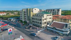A multi-story building with a commercial ground floor, including a real estate office and a food shop. - Palm Aruba 418 | Modern Island Getaway (Palma Real)