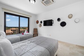 Ein Hotelzimmer mit zwei Betten, einem an der Wand befestigten Fernseher und Blick auf die Stadt.