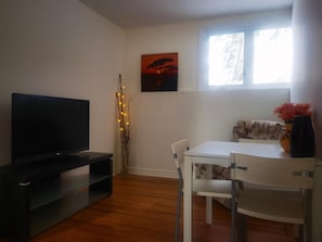 A living room with a flat-screen TV, a white table, and a floral sofa. - A quiet and private small home where you can cook and do laundry. (Ottawa)