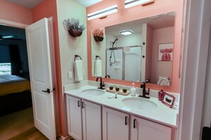 A bathroom with two sinks, a large mirror, and a shower. - 4 BR | 3 BA | New Build | 3-Car Garage | 5 Beds (Omaha)