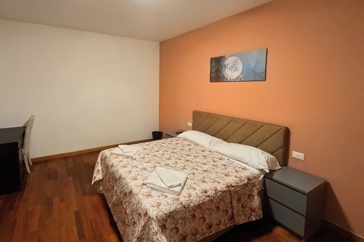 Ein Schlafzimmer mit einem Bett, Nachttischen, einem Sessel und einem Bild an der Wand.