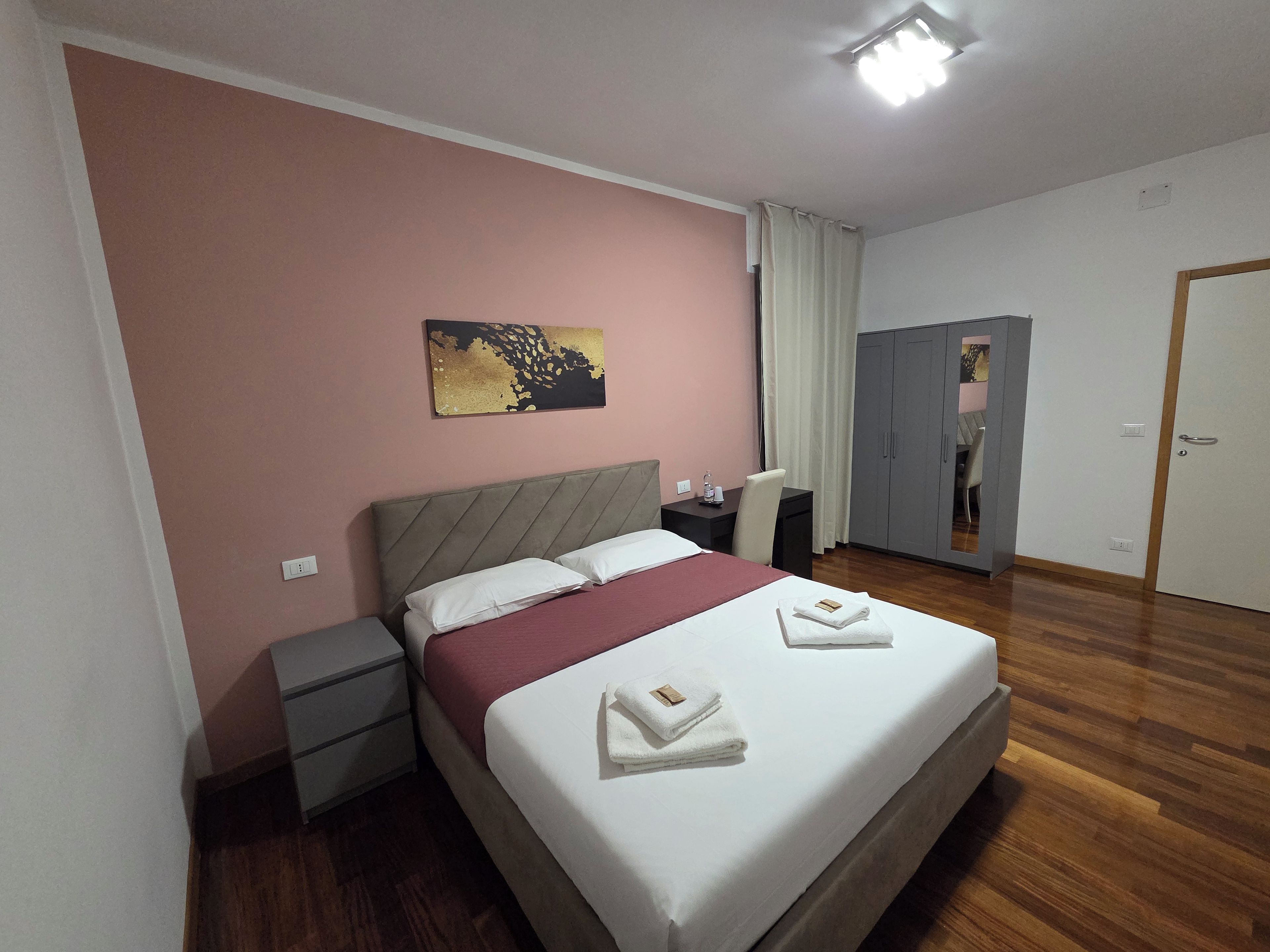 Ein Hotelzimmer mit Bett, Nachttisch und Kleiderschrank.