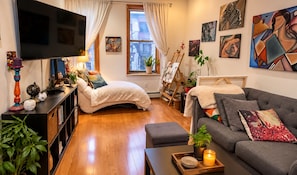 A modern living room with a sofa, a bed, a TV, and artwork on the walls. - 2-bedroom apartment in gorgeous Brooklyn with AC and comfort (Brooklyn)