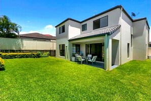 A two-story house with a covered patio and a well-maintained lawn. - Room-spacious Bedroom in Arundel (Gold Coast)