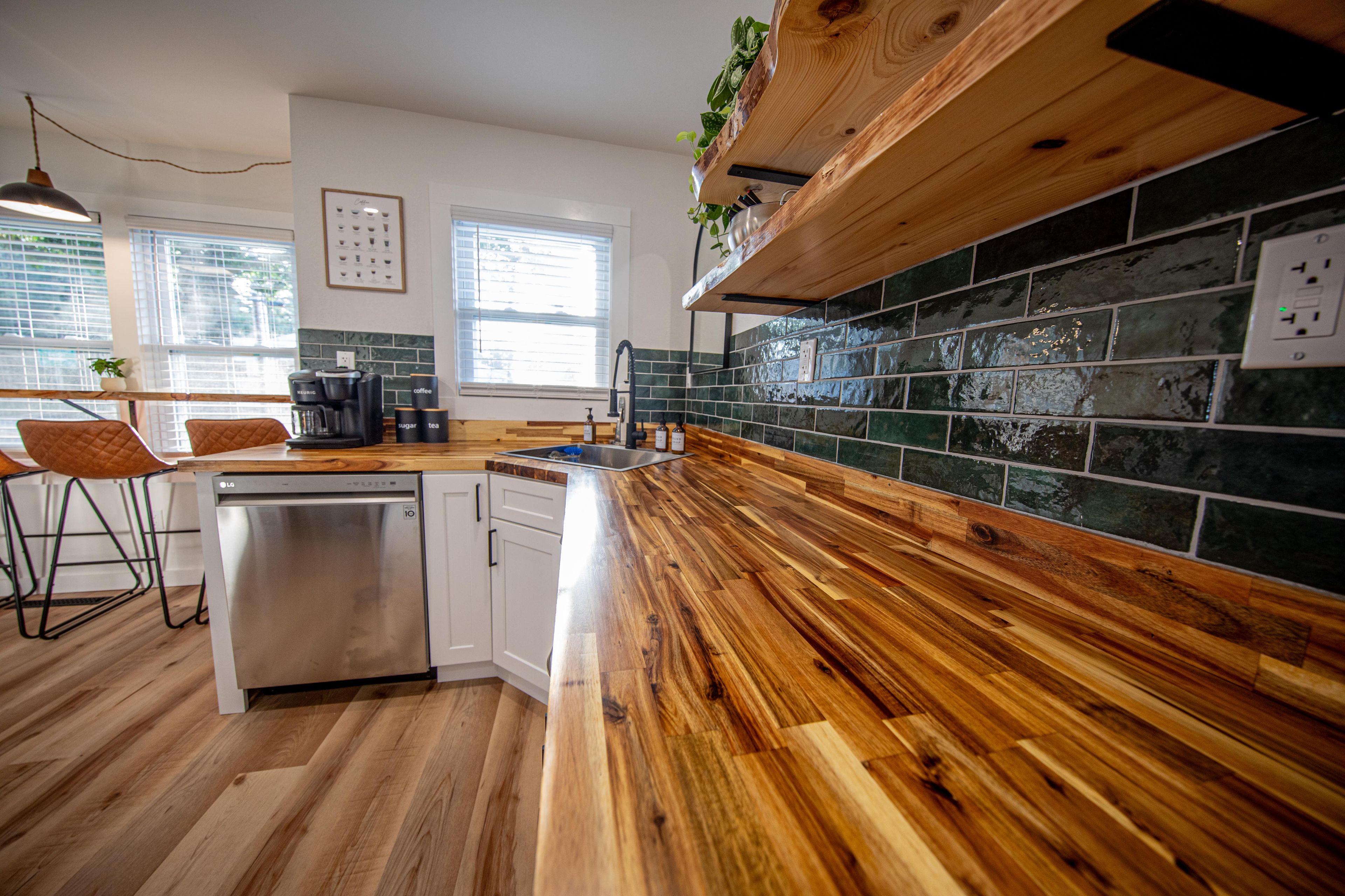 A kitchen with a wooden countertop, a dishwasher, and a sink.