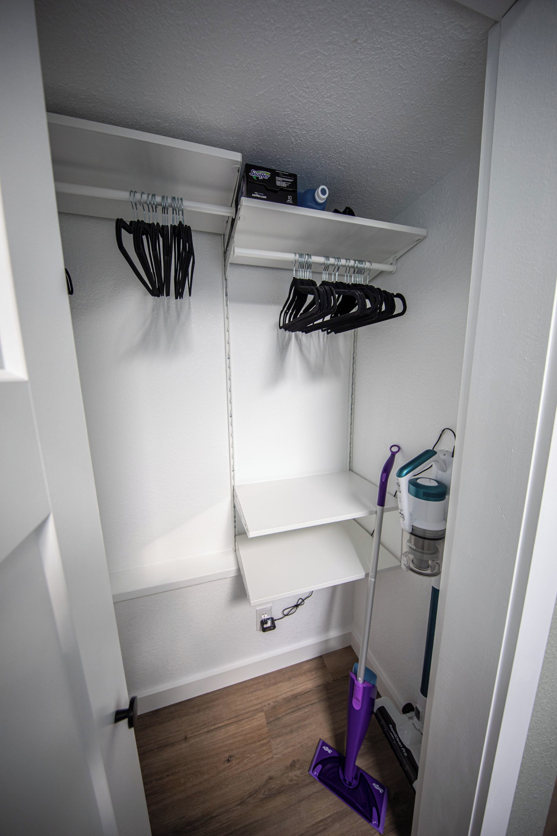 A storage closet with shelves, hooks, and a mop.
