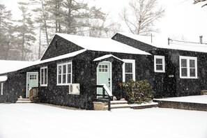 A snow-covered house with a front porch, a small tree, and a visible chimney. - Modern 3-bedroom Duplex in Bethel, EV Charging, 10 mins to Sunday river (Bethel)