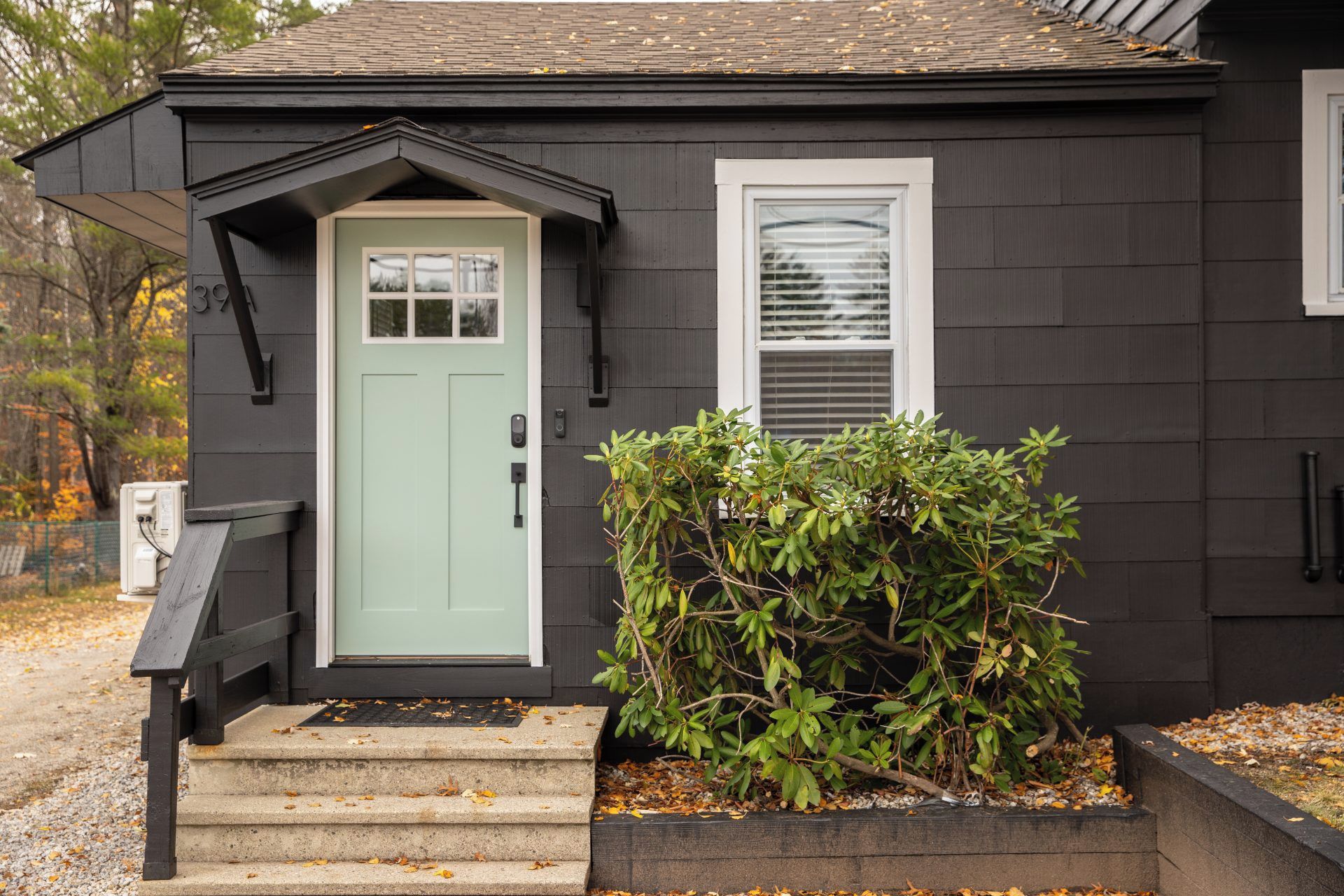A house with a green door, a small porch, and a window with blinds.