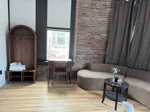 A modern living room with a wooden arched wardrobe, a round table with a vase, and a sofa. - Room 204, Ilium Luxury Hotel Downtown Troy (Troy)