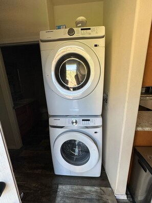 A stacked washer and dryer unit in a laundry room. - Comfy Flat with RiverView (Vida)