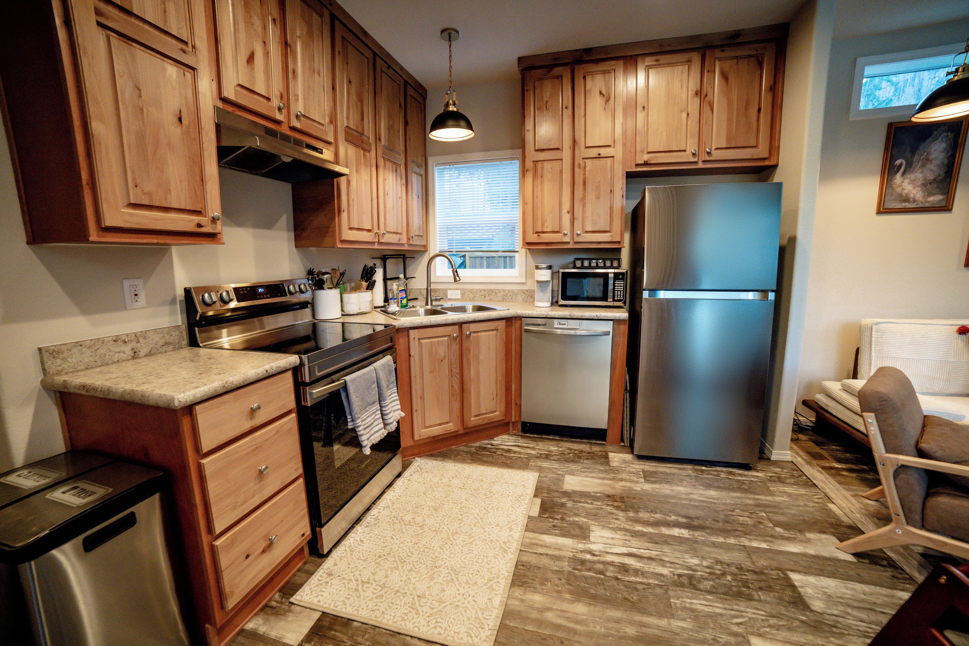 A kitchen with wooden cabinets, stainless steel appliances, a microwave, a dishwasher, and a refrigerator.