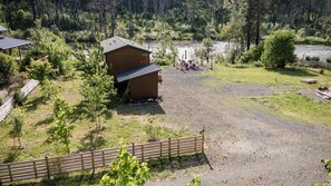 Ein rustikales Blockhaus mit einem Schotterweg, umgeben von Bäumen und bewaldetem Gelände.