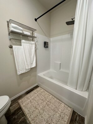 Ein Badezimmer mit einer Badewanne, einer Toilette, einem Handtuchhalter und einem gemusterten Teppich.