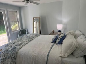 A bedroom with a bed, a chair, a nightstand, and a window. - Renovated Vermont Apartment | Near Stowe & Smugglers' Notch (Cambridge)