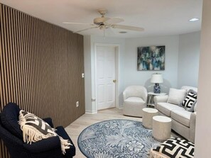 Ein modernes Wohnzimmer mit Deckenventilator, rundem Couchtisch und einer Sofagarnitur.