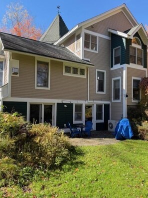 A two-story house with a covered patio and a lawn. - Renovated Vermont Apartment | Near Stowe & Smugglers' Notch (Cambridge)