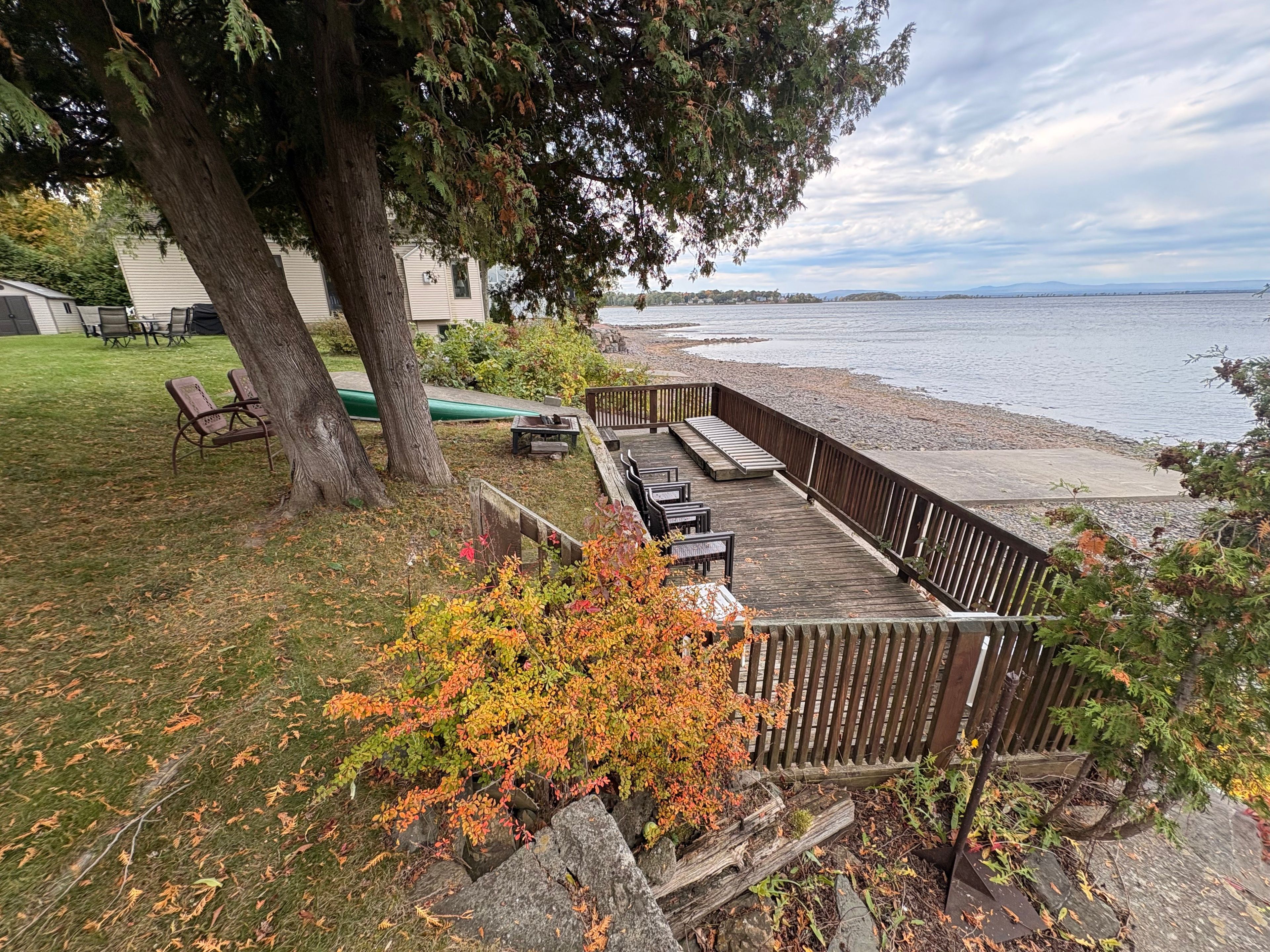 A deck with outdoor seating, a grassy area, and a view of a lake.