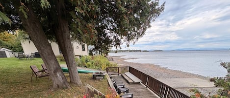 A deck with outdoor seating, a grassy area, and a view of a lake.