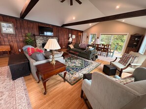A spacious living room with a wooden ceiling, a sofa, a coffee table, and a television. - 3BR lakefront dog friendly home w/ views and kayaks (Colchester)