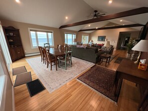 A spacious living area with a dining table, chairs, a sofa, and a fireplace. - 3BR lakefront dog friendly home w/ views and kayaks (Colchester)