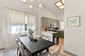 Een moderne keuken met groene kastjes, een magnetron en een roestvrijstalen prullenbak.