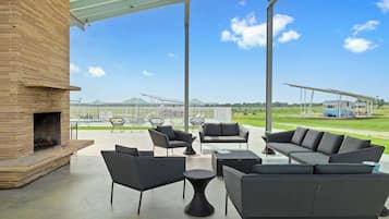 An outdoor patio with a brick fireplace, seating area, and a view of a trailer park.