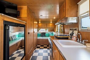 Une cuisine compacte pour camping-car, équipée d’un réfrigérateur, d’un évier et d’un petit coin repas.