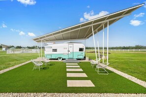 A caravan park with a caravan, outdoor seating, and a covered area. - Blue Skies Resort | Glamping | Pool | Fireplace (Fredericksburg)