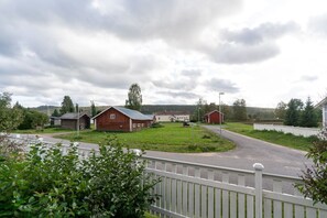 Un paysage rural avec une route asphaltée, une clôture blanche en bois et plusieurs bâtiments en bois.