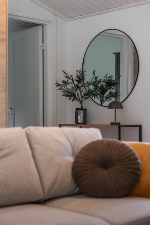 A modern living room with a sofa, a round mirror, and a potted plant. - Nordic apartment IV near SCV (Rovaniemi)