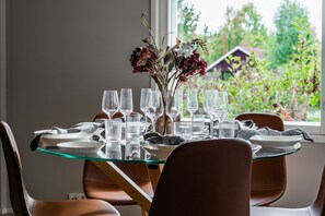 A dining table with multiple glasses and plates, set for a meal, with a vase of flowers in the center. - Nordic apartment IV near SCV (Rovaniemi)