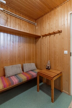 A wooden room with a bench, a table, and a wall-mounted shelf. - Santa's Star Residence - Grand Apartment (Rovaniemi)