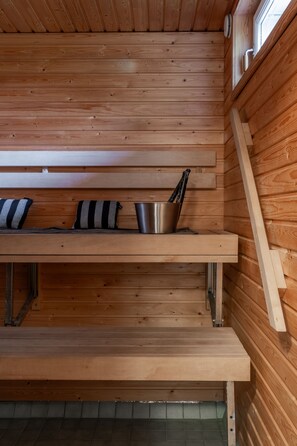 A wooden interior with a bench, a metal cup, and a striped towel. - Santa's Star Residence - Grand Apartment (Rovaniemi)